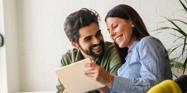 Smiling man and woman looking at a tablet
