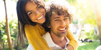 Smiling man carrying smiling woman on his back